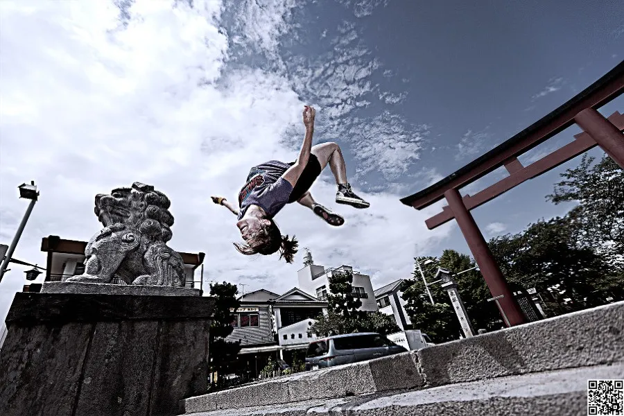 Luci Romberg mid-back flip in a traditional Japanese garden.