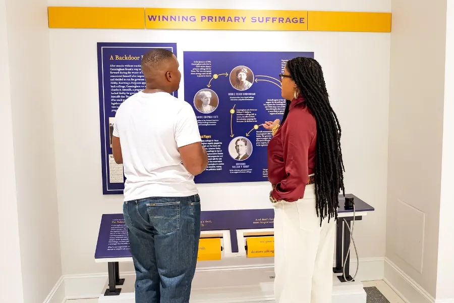 Two adults discuss the Texas suffrage exhibit.