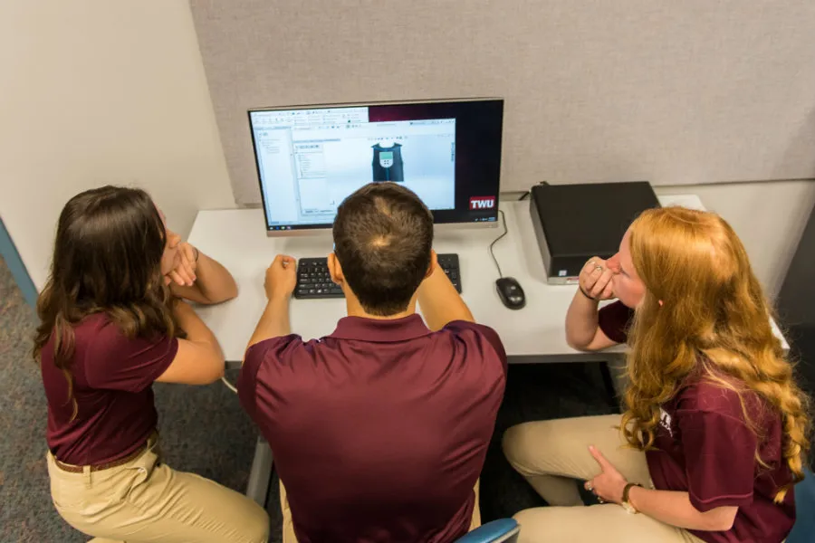 Three TWU students look at a 3D model on a computer screen