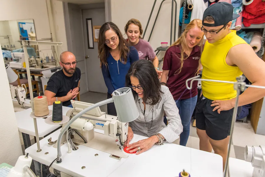 Five TWU students watch as Dr. Dragoo sews the prototype.