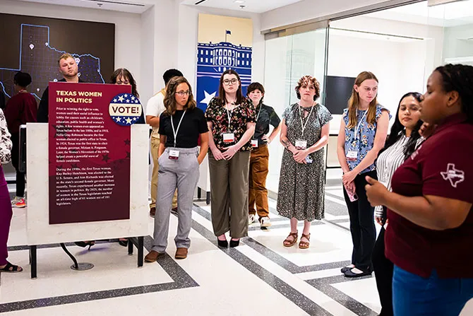 A docent leads a tour group through the Texas Women in Politics area of the Bancroft Leadership Hall