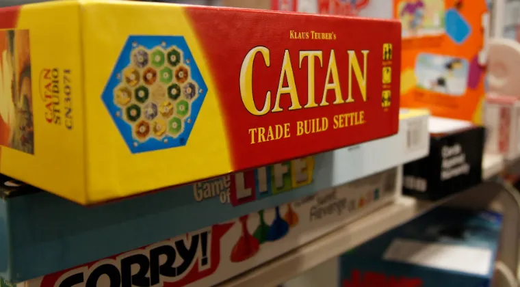 Stack of board games including Sorry!, Catan, and Life