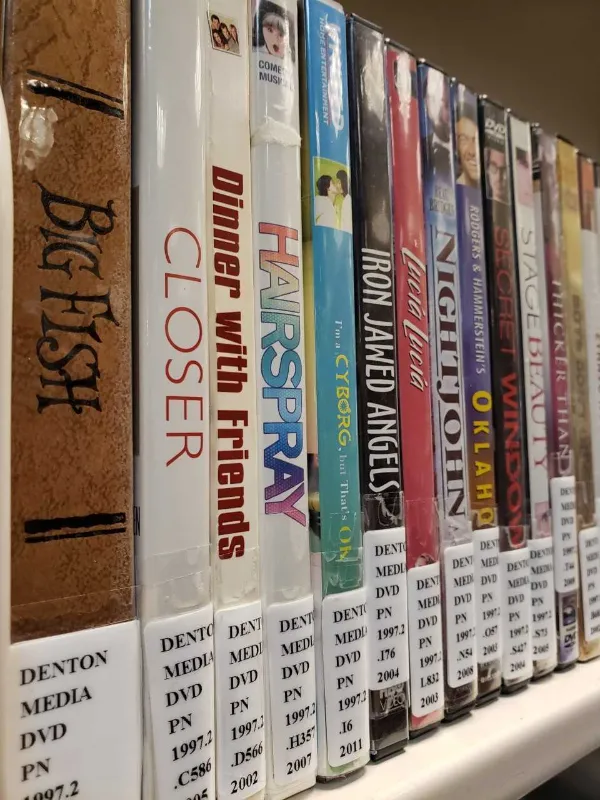A row of DVDs on a shelf with call numbers showing