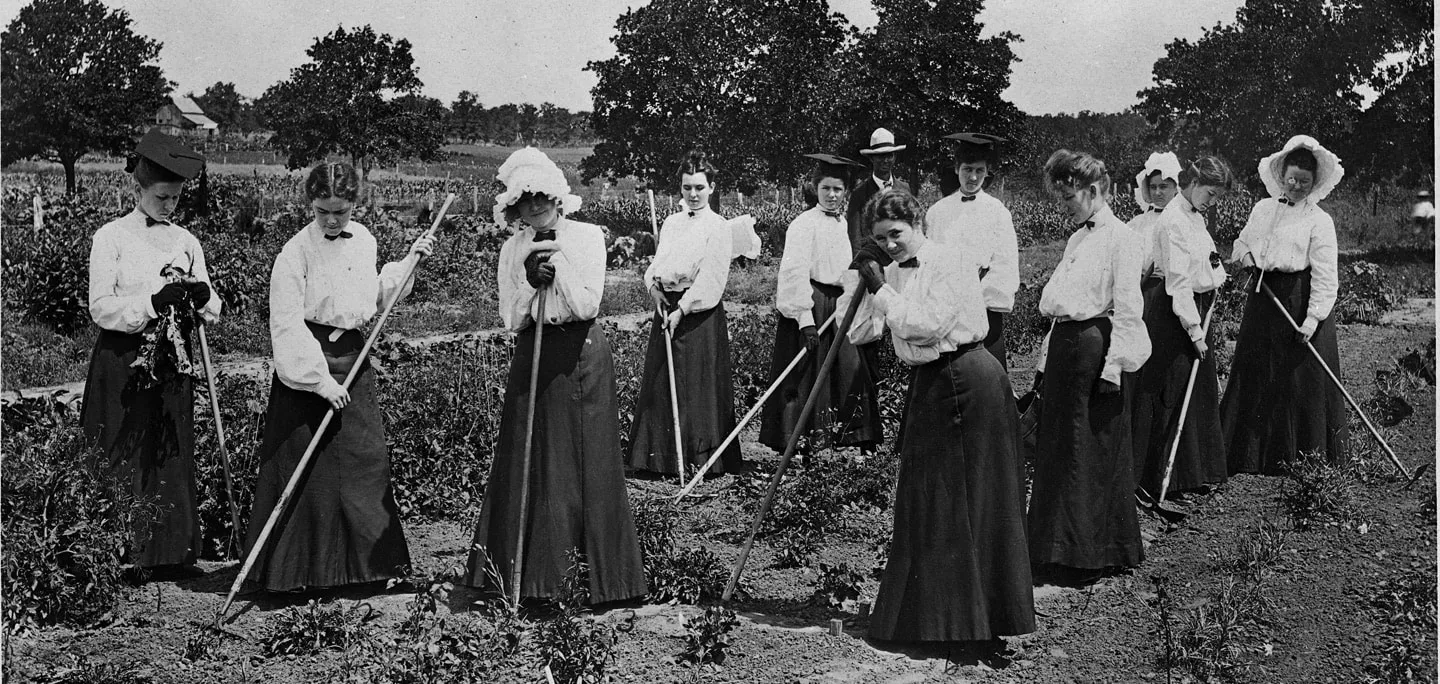 Gardening students stand in a tilled plot holding rakes, ca. 1907, College of Industrial Arts, Denton, Texas.