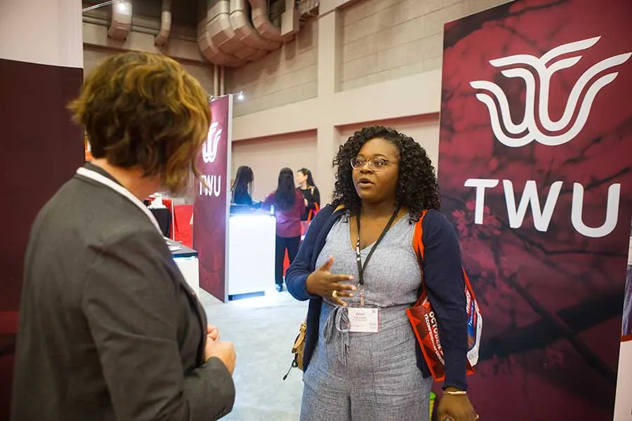A TWU employee at a conference in front of a TWU retractable banner.