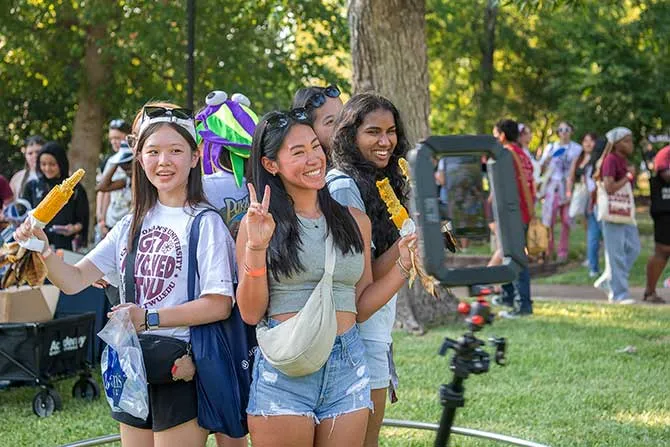 Four TWU students at an outdoors event take a photo with a selfie camera.