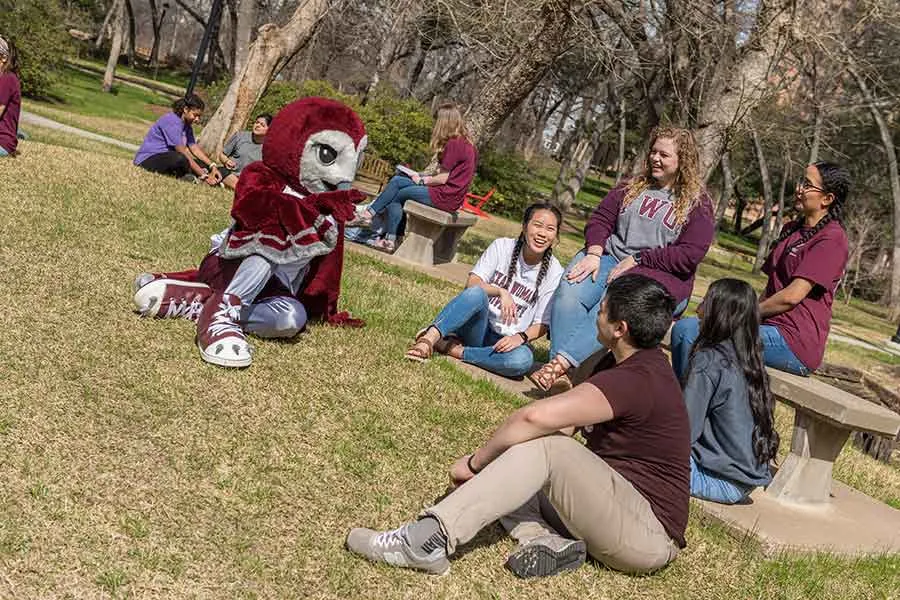 TWU students lounging on the lawn with Oakley. 