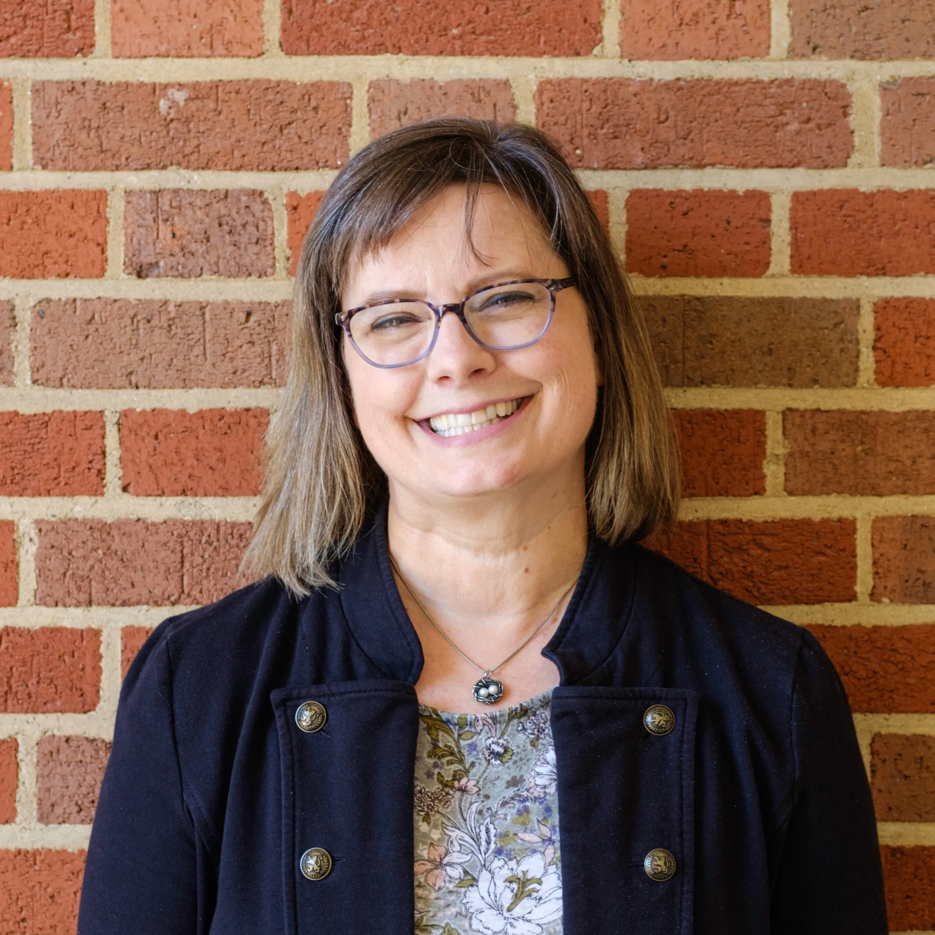 Della in front of a red brick wall