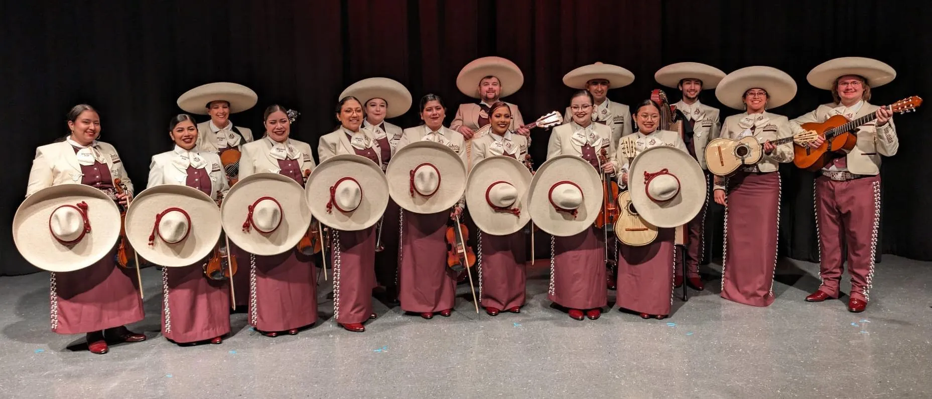 A group of mariachi musicians in trajes on stage 