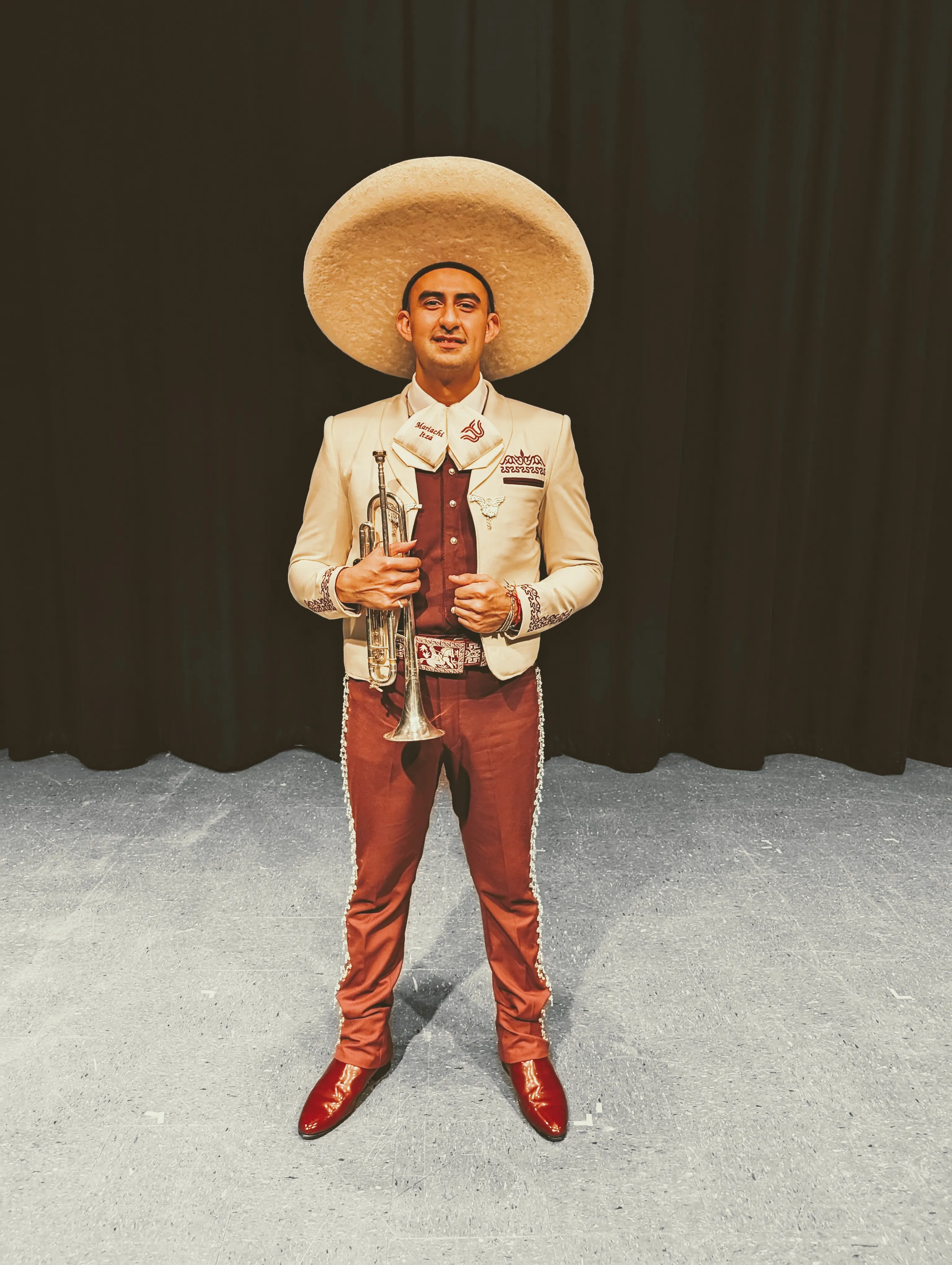 Jason in a mariachi traje holding a trumpet