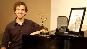 Sean with an Emmy award trophy near a piano
