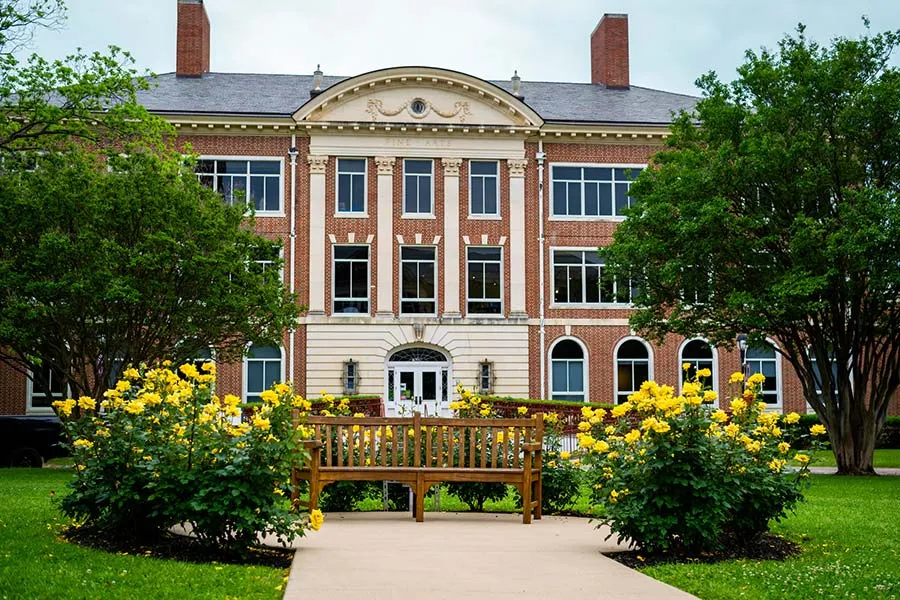 A park bench on the Pioneer Circle surrounded by bright yellow flowers.