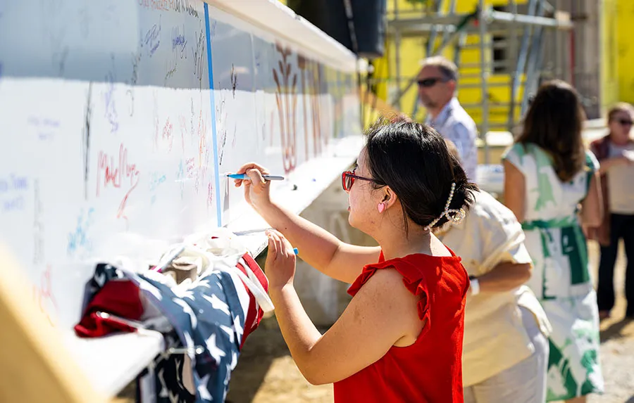 People sign their names to the final beam before it is placed on the new HSC building