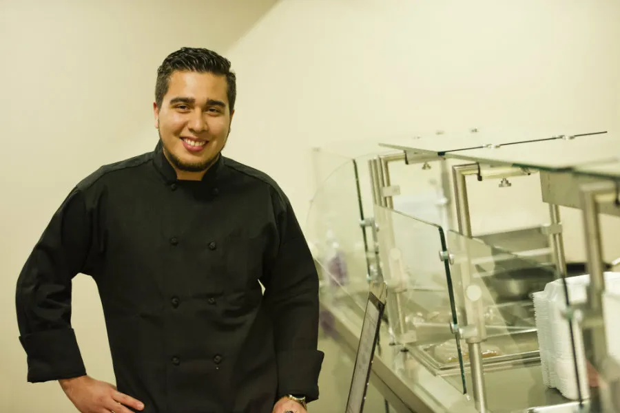 Walter Rivas in his chef uniform and posing in his kitchen. 