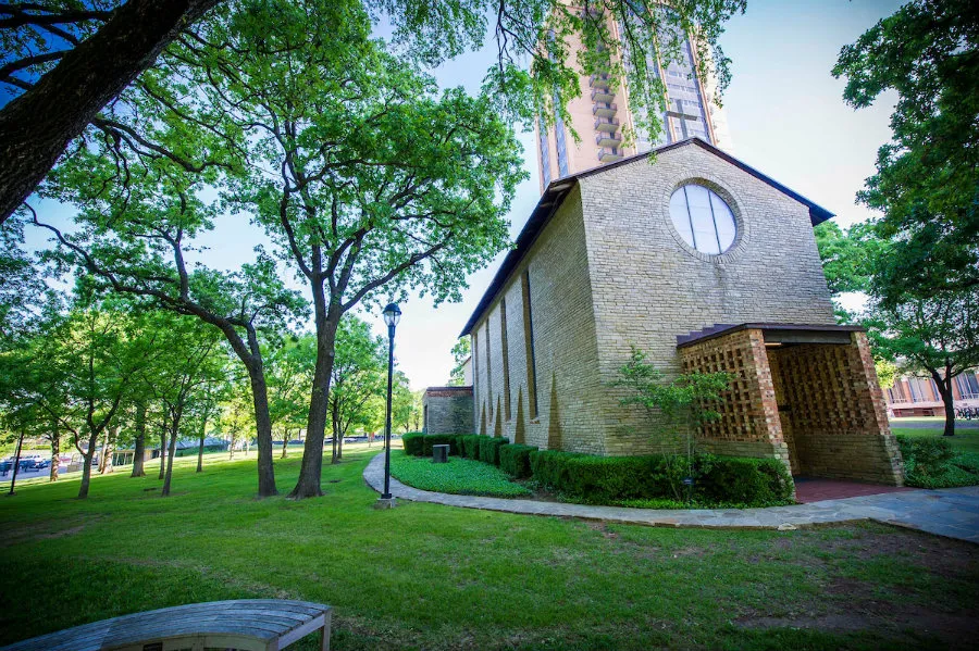 Brick chapel surrounded by trees and grass 