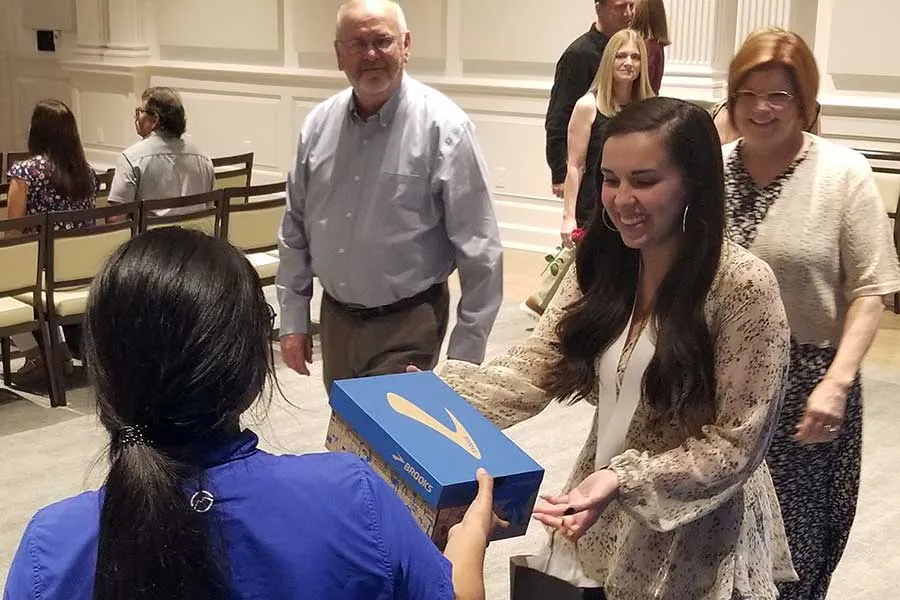 A BSN graduate accepts her new pair of Brooks shoes from Academy
