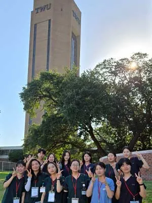 Visiting Korean nursing students pose in front of TWU's tower