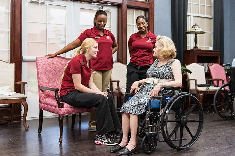 Three TWU OT students discuss care options with an elderly woman in a wheelchair