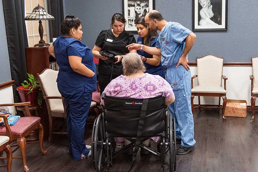 A group of medical professionals discuss options with an elderly patient in a wheelchair