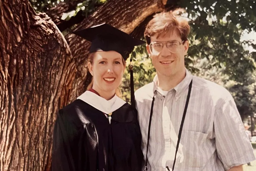 Lou Ann Hintz, in graduation regalia, stands with her husband