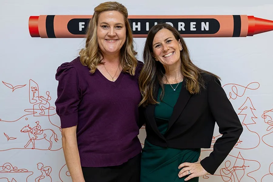 Angela Shierk and Heather Roberts stand in front of a Scottish Rite backdrop