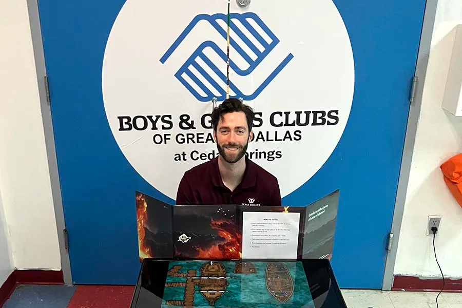 TWU student Jeremiah Stevens stands behind a desk with a Dungeons & Dragons game