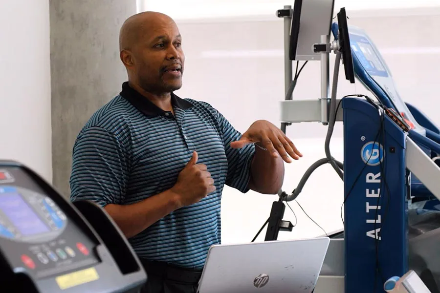 Professor Wayne Brewer stands behind a laptop and next to some medical equipment