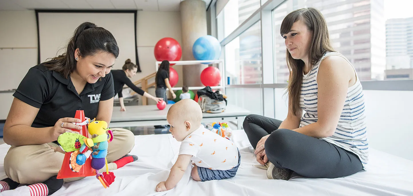 A TWU physical therapy student works with a small toddler