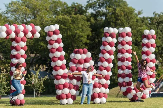 TWU students jump in front of TWU balloons at Block Party