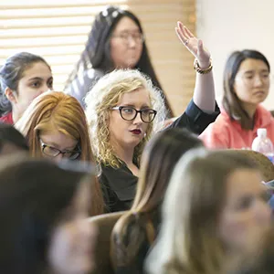 A student with her hand raised in a classroom