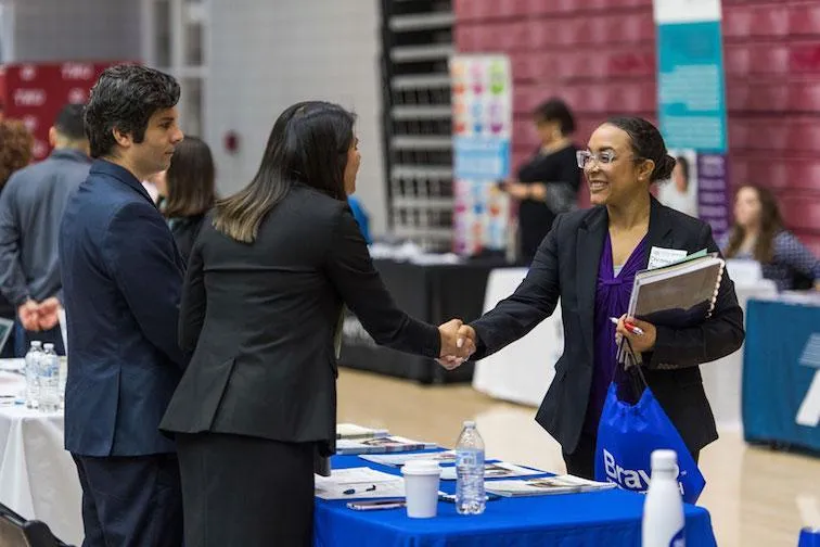 A prospective employee shakes hands with a recruiter