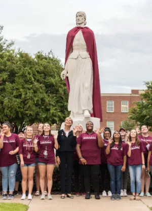 Chancellor Feyten stands with a group of students in front of the Pioneer Woman statue
