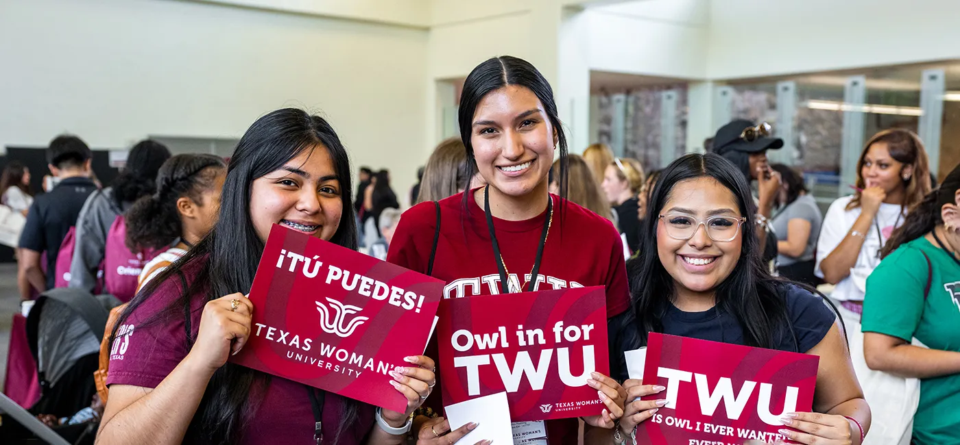 Three students hold signs that display they have picked to attend TWU.