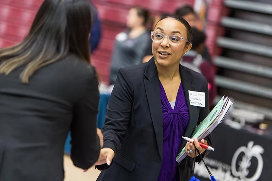 Two women shake hands at a hiring fair