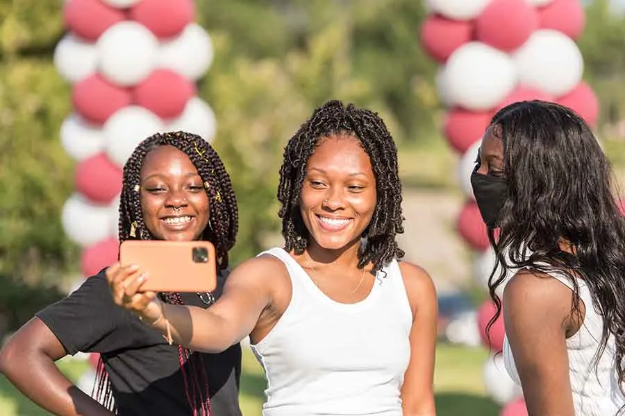 Three TWU students take a photo at an on campus event.