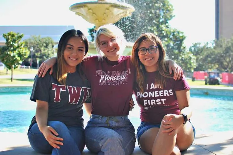 Three TWU students sitting on the edge of the library fountain
