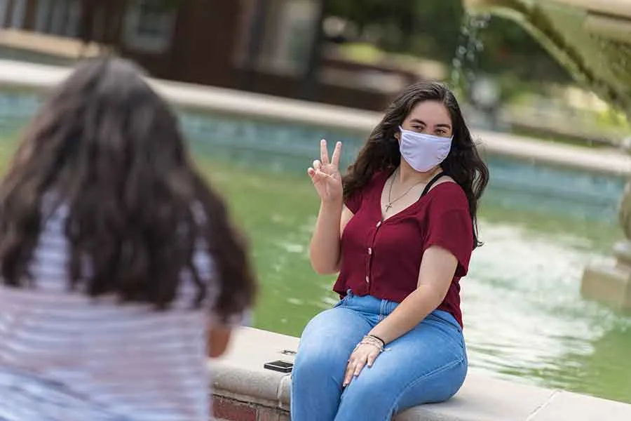 a TWU student poses at the fountain on the Denton campus.