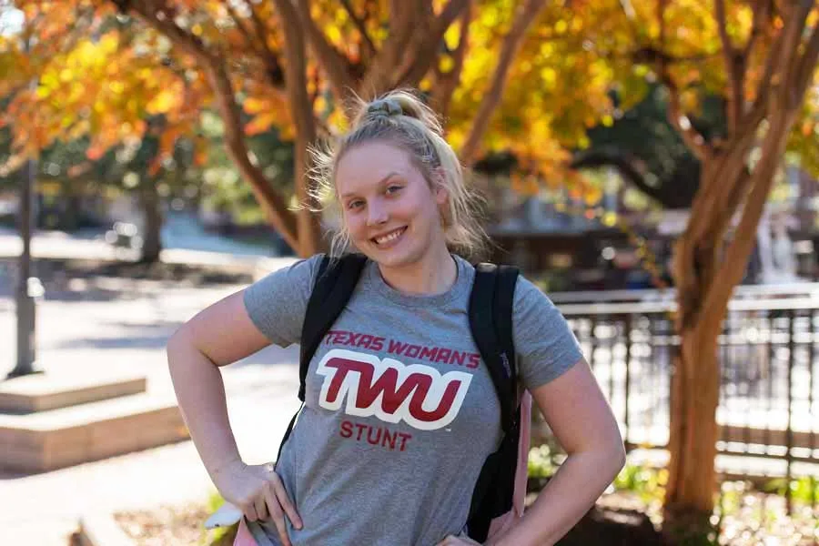 A TWU student on campus in a TWU STUNT team shirt.