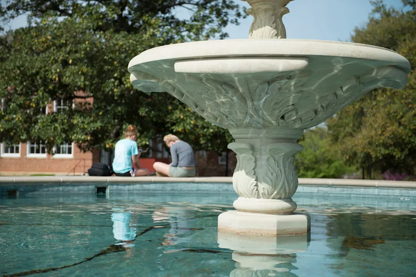 Two students sitting at the TWU fountain 