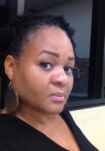 Side profile of woman with dark hair and skin lookin at camera outside