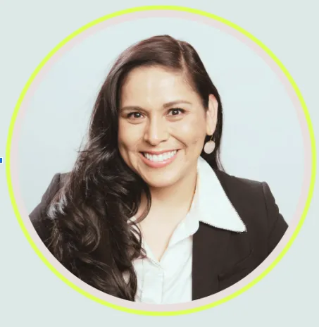 Woman with long dark hair in a black blazer and white top smiles in front of white background