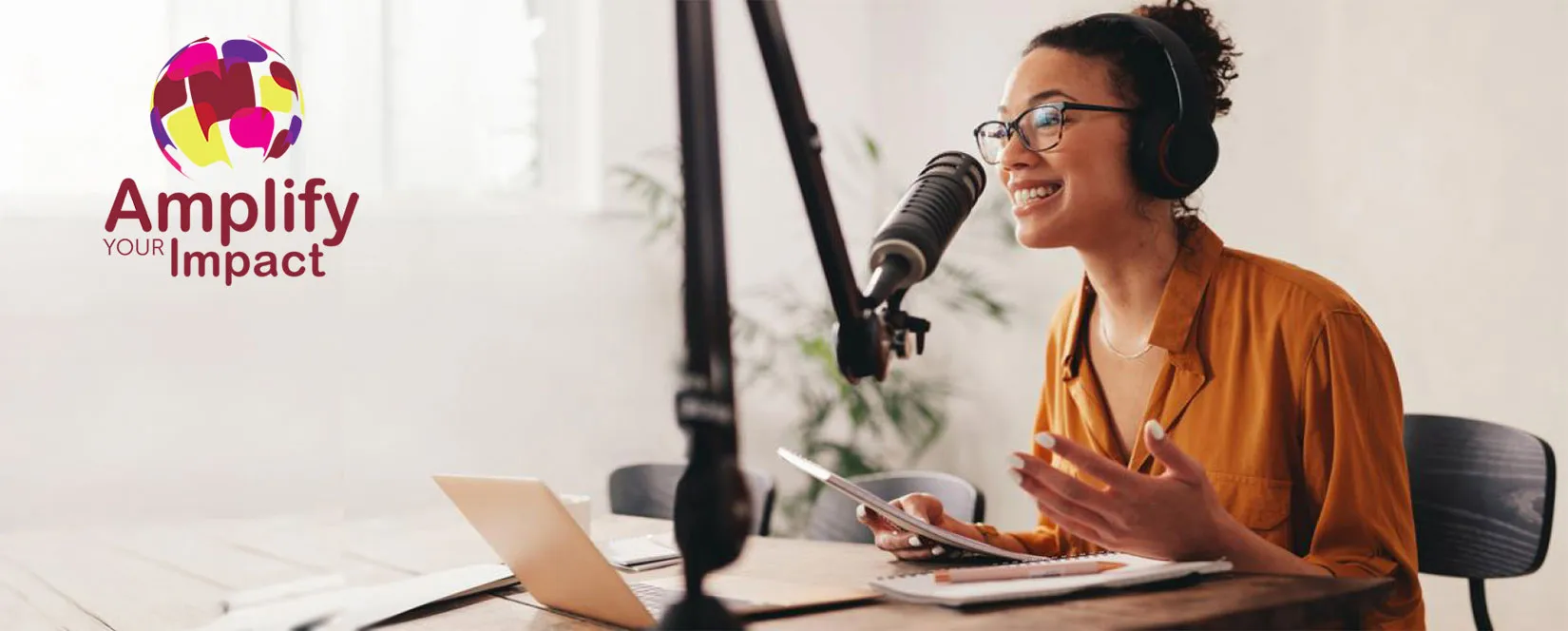 A woman smiling into a microphone as she records a podcast