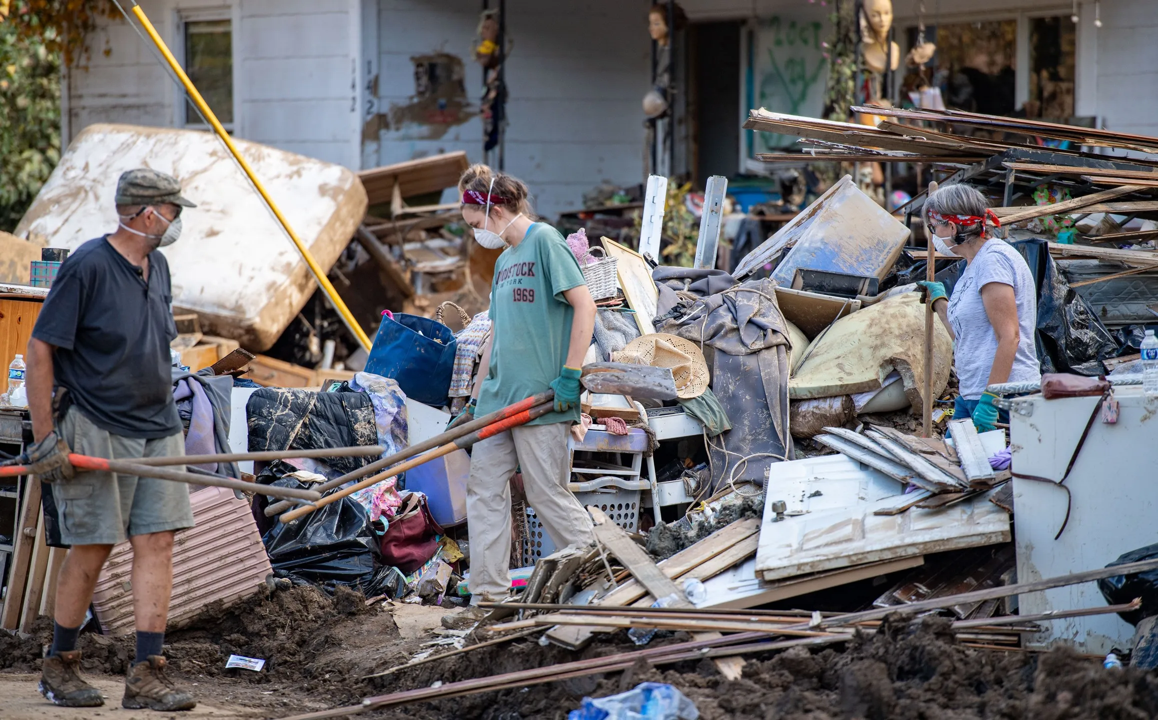 Photo of people trying to pick up debris resulting from houses being washed away by a hurricane