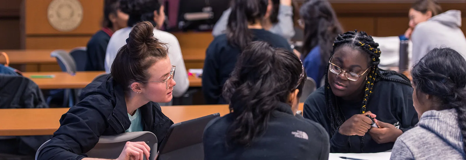 Four students collaborate together around a long classroom desk