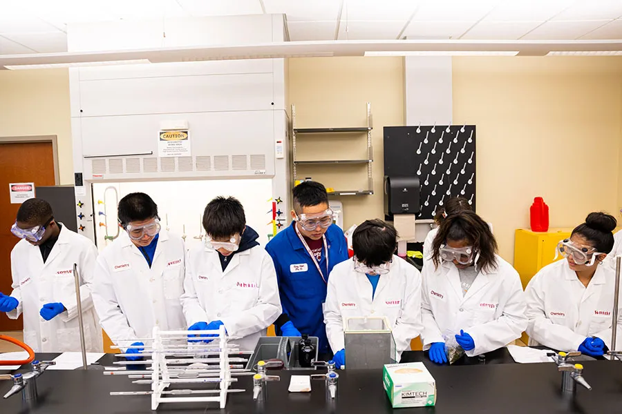 High school students work in a TWU chemistry lab with a professor.