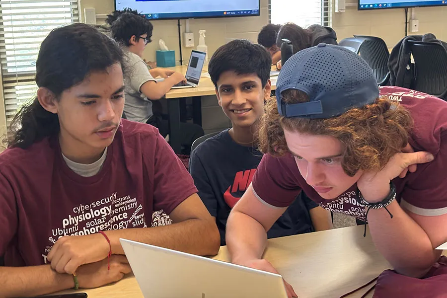High school students work in a classroom setting at a computer for Cyber Camp.
