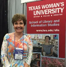 A woman smiling in front of a Texas Woman's University banner. 
