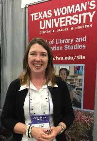 A woman smiling in front of a Texas Woman's University banner. 