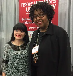 Two women smiling in front of a Texas Woman's University banner. 