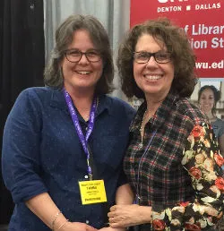 Two women smiling at a convention. 